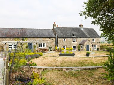 A stone house with a garden and patio furniture at The Shooting Lodge in Longnor