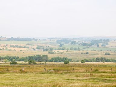 A rural landscape with fields trees and a farm building at The Shooting Lodge in Longnor