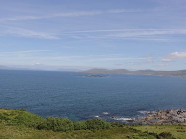 A coastal landscape with ocean water rocky shoreline and distant hills at Seaspray in Tully County Galway