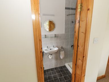 A small bathroom with a sink mirror towel ring and shower at Seaspray in Tully County Galway