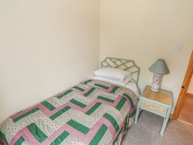 A bedroom with a single bed next to a bedside table with a lamp at Seaspray in Tully County Galway