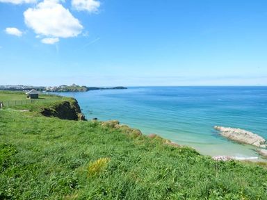 A coastal view with green cliffs and blue sea under a clear sky at Saltwater One Lusty Glaze in Newquay