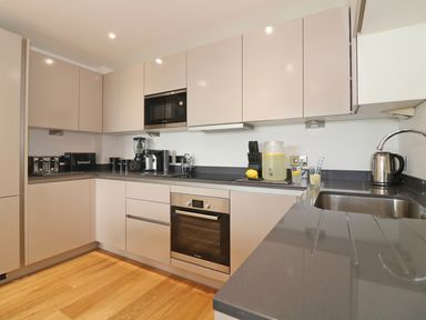 A kitchen with beige cabinets black countertops stainless steel appliances and a sink at Saltwater One Lusty Glaze in Newquay