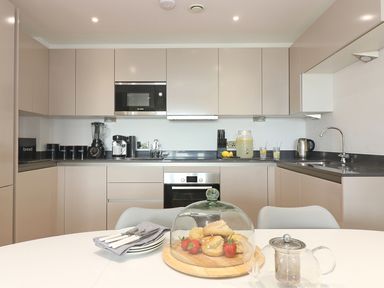 A kitchen with beige cabinets coffee machine microwave and baking on a table at Saltwater One Lusty Glaze in Newquay