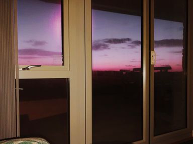 A window and sliding glass door showing a purple and pink sunset sky
