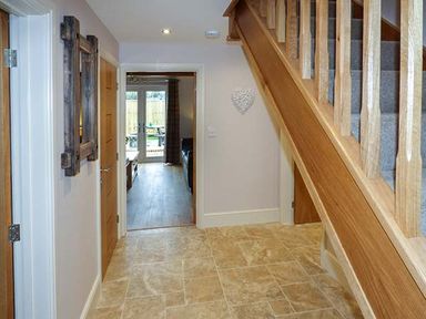 A hallway with tiled floor wooden staircase and doors leading to another room with glass doors at Rose Cottage in Winforton near Hay-on-Wye