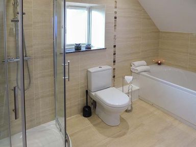 A bathroom with a shower cubicle toilet and bathtub with towels at Rose Cottage in Winforton near Hay-on-Wye