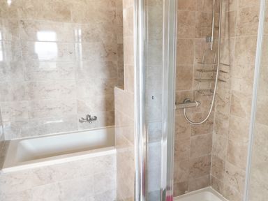 A bathroom with a bathtub and a separate shower area with tiled walls at View The Gallery in Okehampton
