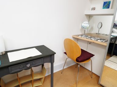 A small corner with a wooden chair and a vanity table with mirrors and a cushion at View The Gallery in Okehampton
