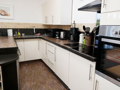 A kitchen with white cabinets a countertop sink coffee maker toaster kettle stove and oven at View The Gallery in Okehampton