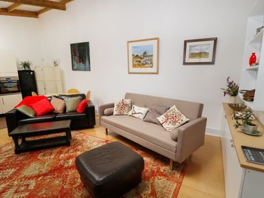A living room with two sofas pillows coffee table and framed paintings at View The Gallery in Okehampton