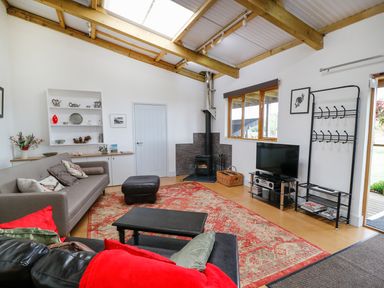 A living room with a sofa television wood stove and shelves at View The Gallery in Okehampton