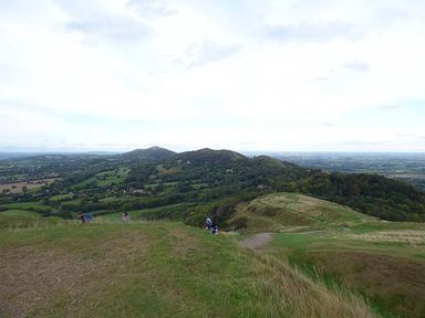 A hilly landscape with grassy fields and scattered trees near Little Malvern near Malvern