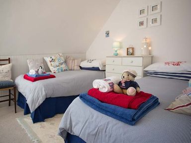 A bedroom with two single beds a chest of drawers and a chair at Kilcarreg Rock near Wadebridge