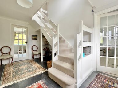 A hallway with stairs and chairs at Kilcarreg in Rock near Wadebridge