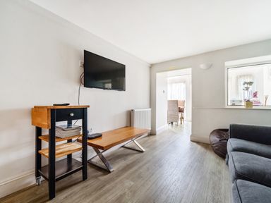 A living room with a wall mounted television a wooden cart table a coffee table a gray sofa and a bean bag at The Oaks in Bowness Windermere