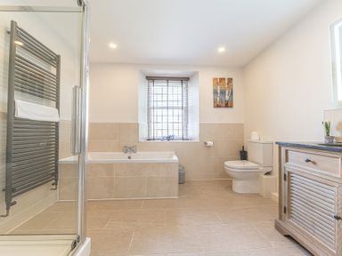 A bathroom with a shower enclosure bathtub toilet and wooden cabinet at The Oaks in Bowness & Windermere