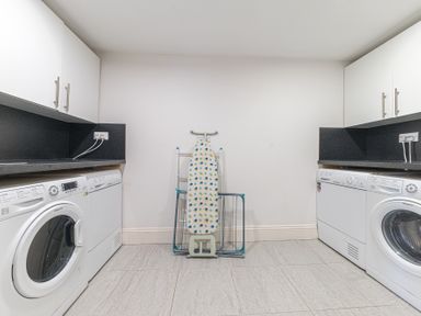 A laundry room with two washing machines two dryers a folded ironing board and drying racks at The Oaks in Bowness & Windermere