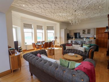 An open plan living room and kitchen with sofas pillows dining table and chandelier at Menai View near Menai Bridge
