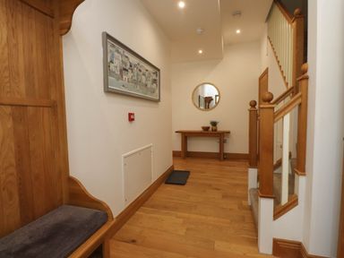A hallway with wooden flooring wooden staircase and a wooden bench with cushion at Menai View near Menai Bridge