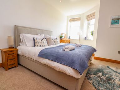 A bedroom with a double bed pillows bedside table lamp and a round rug at Menai View near Menai Bridge