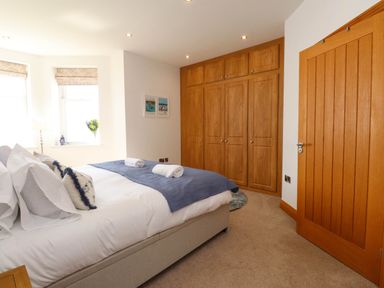 A bedroom with a double bed and built in wooden wardrobes at Menai View near Menai Bridge