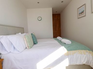 A bedroom with a bed with pillows and rolled towels on a blanket at Menai View near Menai Bridge