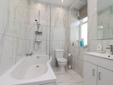 A bathroom with a bathtub shower toilet sink and cabinet at Menai View near Menai Bridge