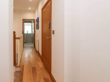 A hallway with wooden flooring and doors leading to other rooms at Menai View near Menai Bridge