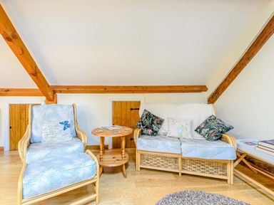 A room with a chair and a sofa with cushions and a small wooden table between at The Bothy in Phocle Green near Ross-on-Wye