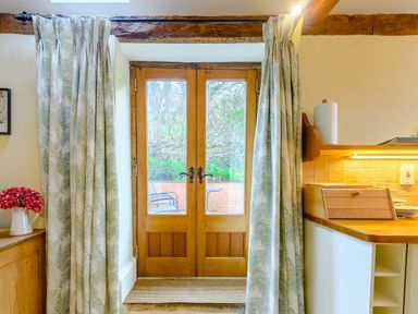 A wooden door with glass panels and curtains leading to an outdoor patio at The Bothy in Phocle Green near Ross-on-Wye