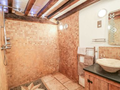 A bathroom with a walk-in shower with tiled walls and floor a wooden vanity with a vessel sink and a towel rack at The Milking Parlour in Highampton