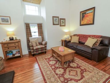 A living room with a sofa and armchair at Rosslare Cottage in Broughshane