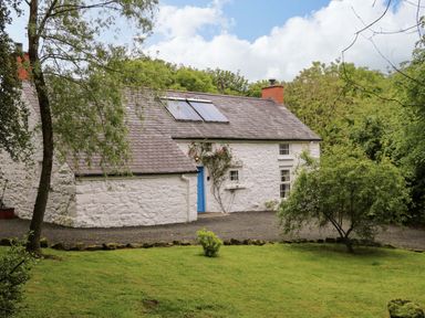 A cottage with a garden and trees at Rosslare Cottage in Broughshane