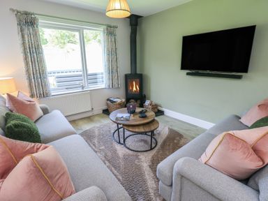 A living room with a fireplace and sofas at Yew - Woodland Cottages Bowness-On-Windermere