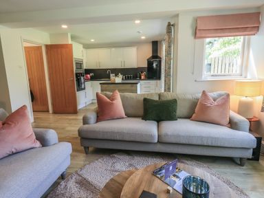 A living room with a sofa and kitchen area at Yew - Woodland Cottages Bowness-On-Windermere
