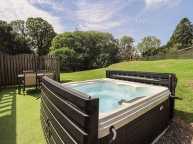 A hot tub with a table and chairs in a garden at Yew - Woodland Cottages Bowness-On-Windermere