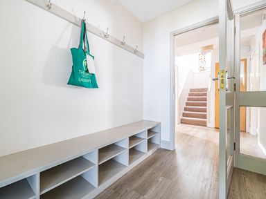 A hallway with a built-in bench and cubby storage a door leading to carpeted stairs at Beech - Woodland Cottages in Bowness-on-Windermere