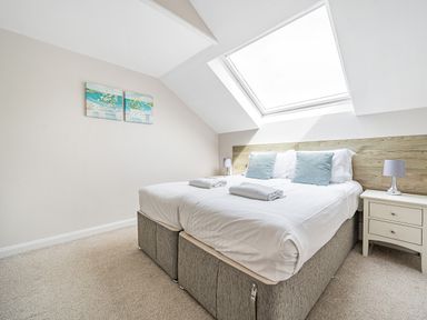 A bedroom with a double bed two nightstands and a skylight window at Beech - Woodland Cottages in Bowness-on-Windermere
