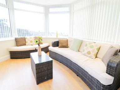 A room with wicker sofas with cushions and a glass top wicker coffee table at Arnant in Barmouth