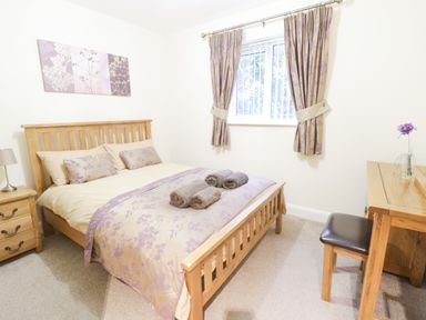 A bedroom with a double bed wooden side table and a wooden dressing table with stool at Arnant in Barmouth