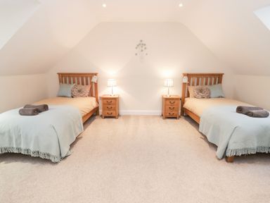 A bedroom with two single beds side by side each with pillows bedside tables and lamps at Arnant in Barmouth