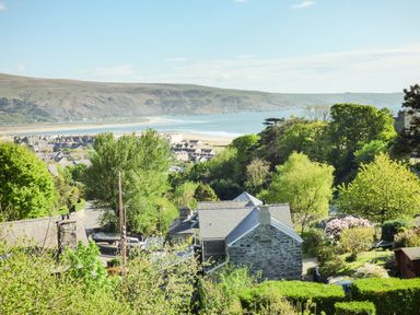 A coastal town with stone houses trees and a beach by the sea at Arnant in Barmouth