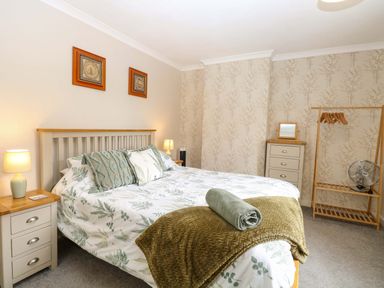 A bedroom with a bed and bedside tables at Fern Cottage in Heacham