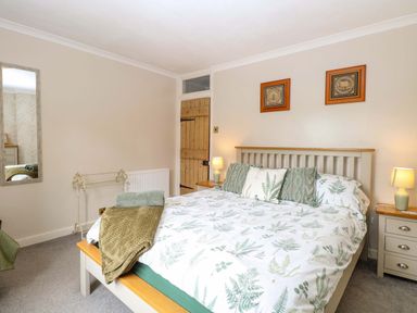 A bedroom with a bed and bedside tables at Fern Cottage Heacham