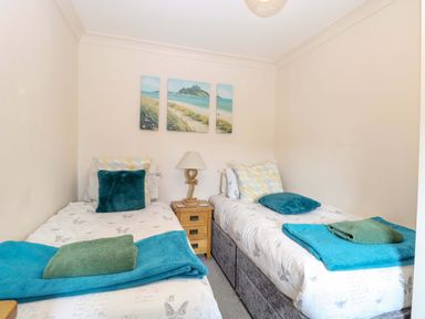 A bedroom with two single beds and wall art at Fern Cottage in Heacham