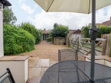 A garden with a table and chairs under an umbrella at Fern Cottage in Heacham
