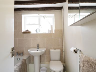A small bathroom with a pedestal sink toilet and bathtub with towels at Causeway Cottage in Pencombe