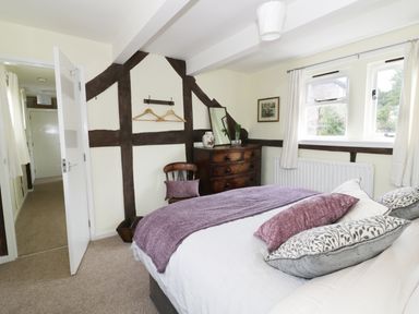 A bedroom with a bed pillows a chair and a chest of drawers at Causeway Cottage in Pencombe