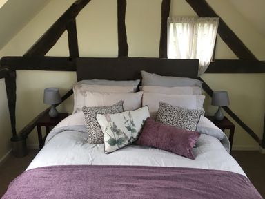 A bedroom with a double bed multiple pillows bedside tables and lamps at Causeway Cottage in Pencombe